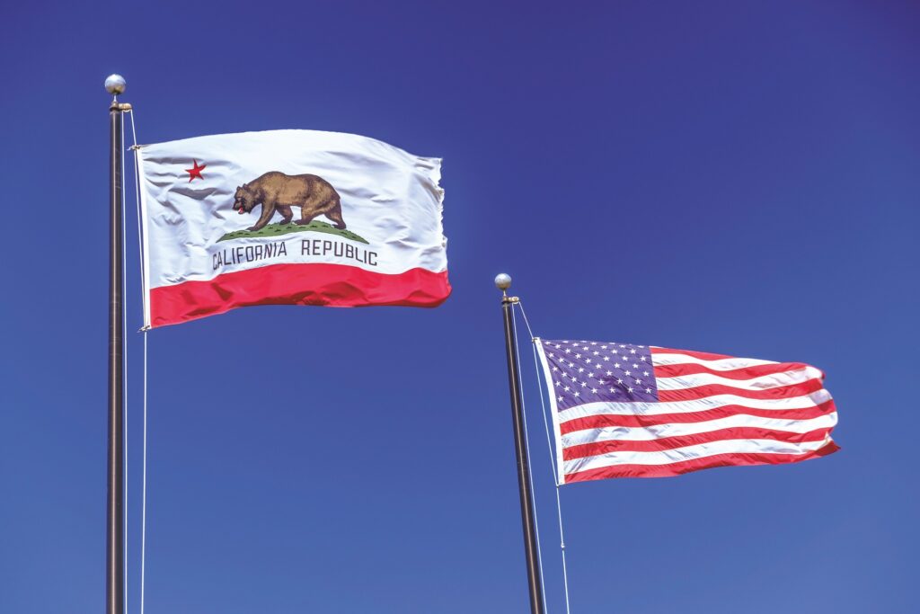 The state flag of California flies alongside the flag of the USA against a blue sky background representing CPRA enforcement